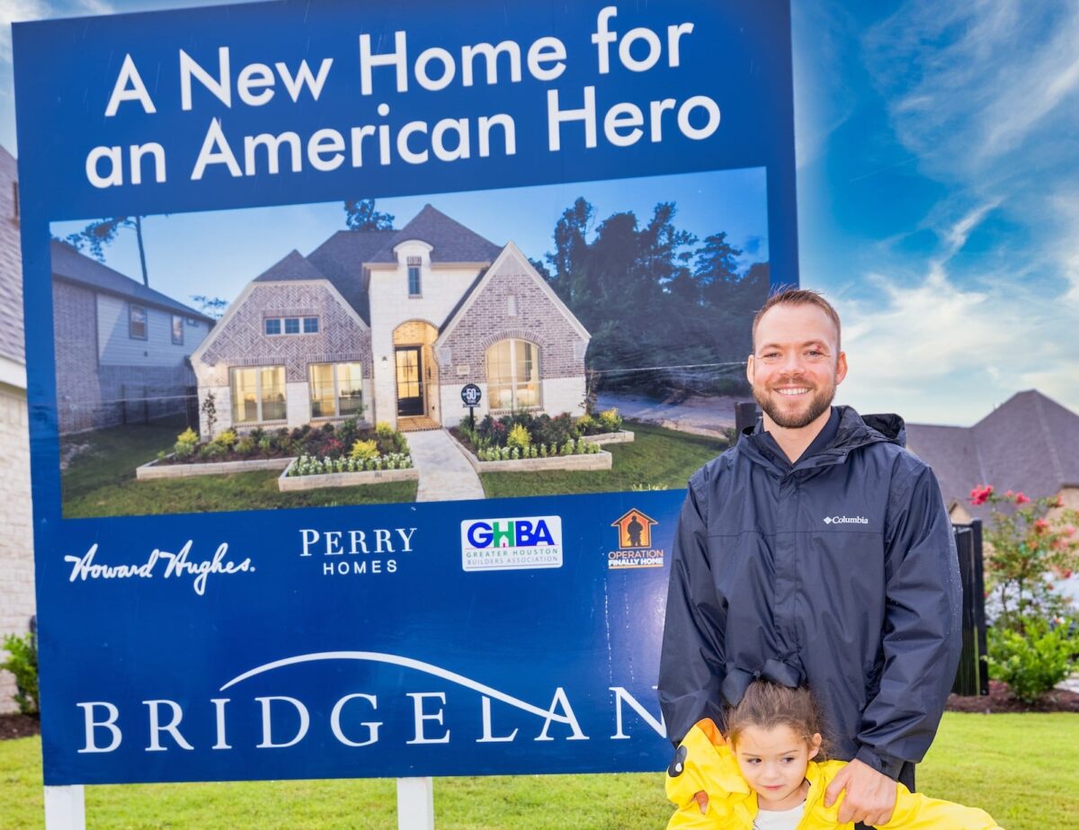 Adult and child in front of a new home sign
