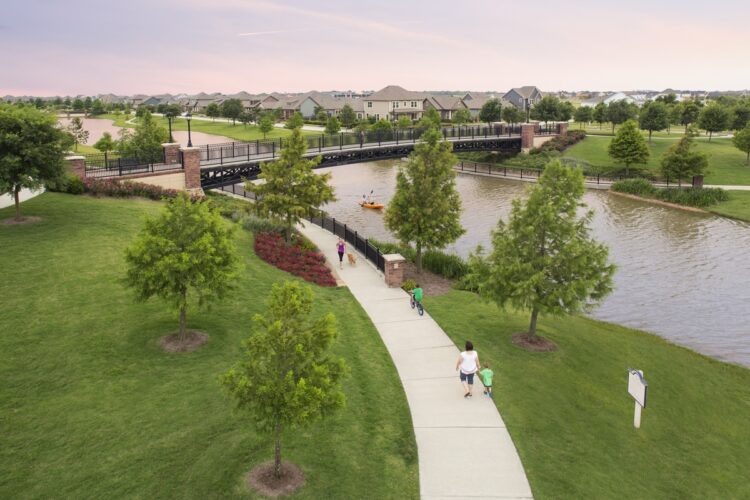 A multifamily development with a bridge over a river offering a resort-style amenities.