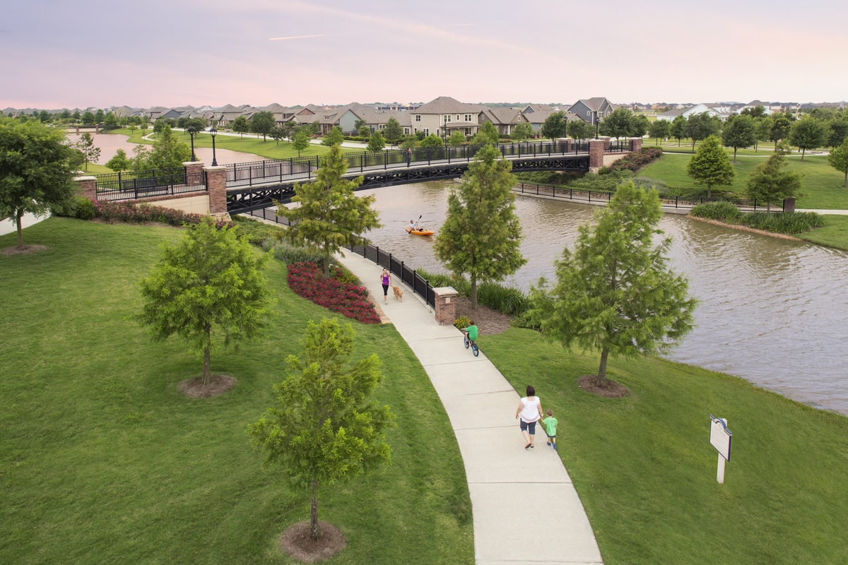 A multifamily development with a bridge over a river offering a resort-style amenities.