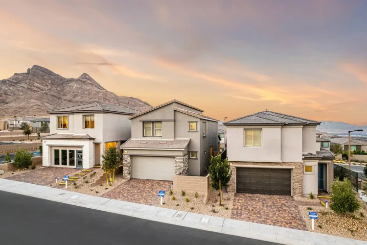 Three modern two-story Lennar houses with stone accents and landscaped front yards are lined up on a Summerlin suburban street, with mountains in the background at sunset.