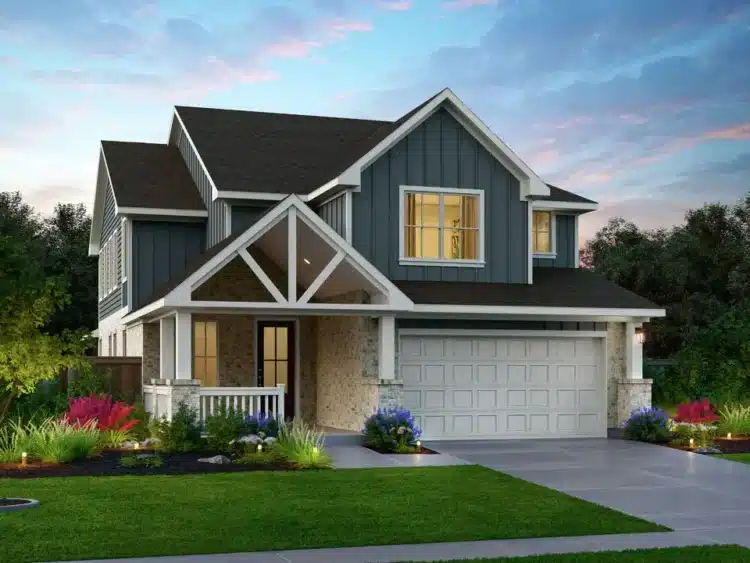Two-story modern house with gray siding, white trim, covered porch, double garage, manicured lawn, and colorful landscaping, photographed at dusk.