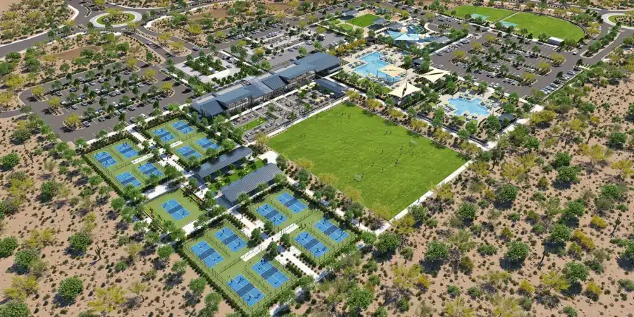 Aerial view of a large recreational complex with tennis courts, soccer fields, parking lots, swimming pools, buildings, and surrounding desert landscape.